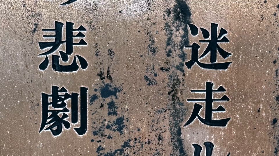 A weathered trail plaque: 悲劇 (tragedy) on the left, 迷走 (lost) on the right.